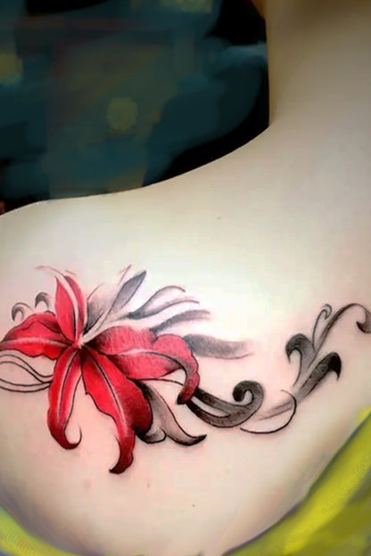A womans wearing a dark yellow to displays the rocking red lilly tattoo on her shoulder teh