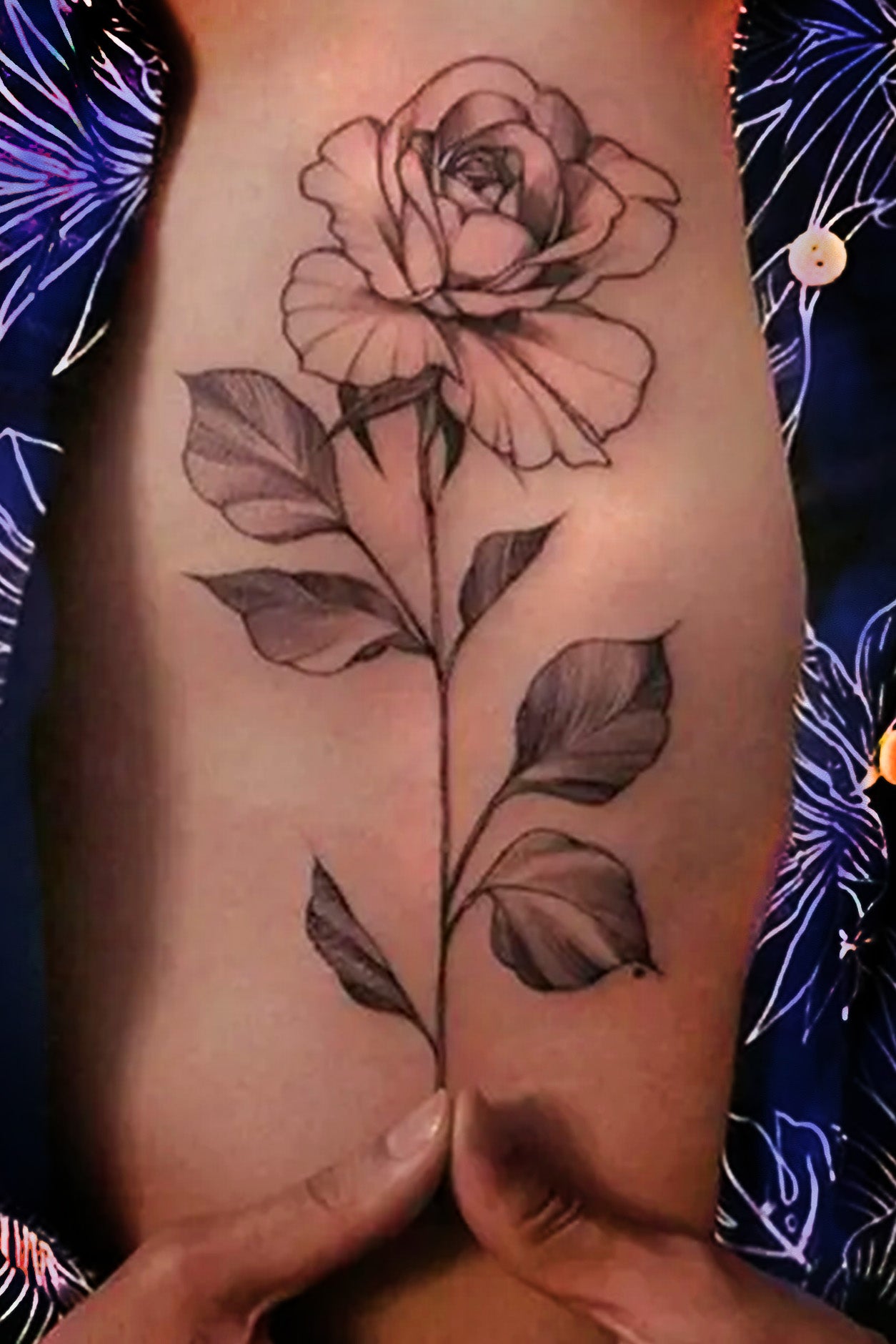 A gender-neutral torso displays the traditional black ink single. rose