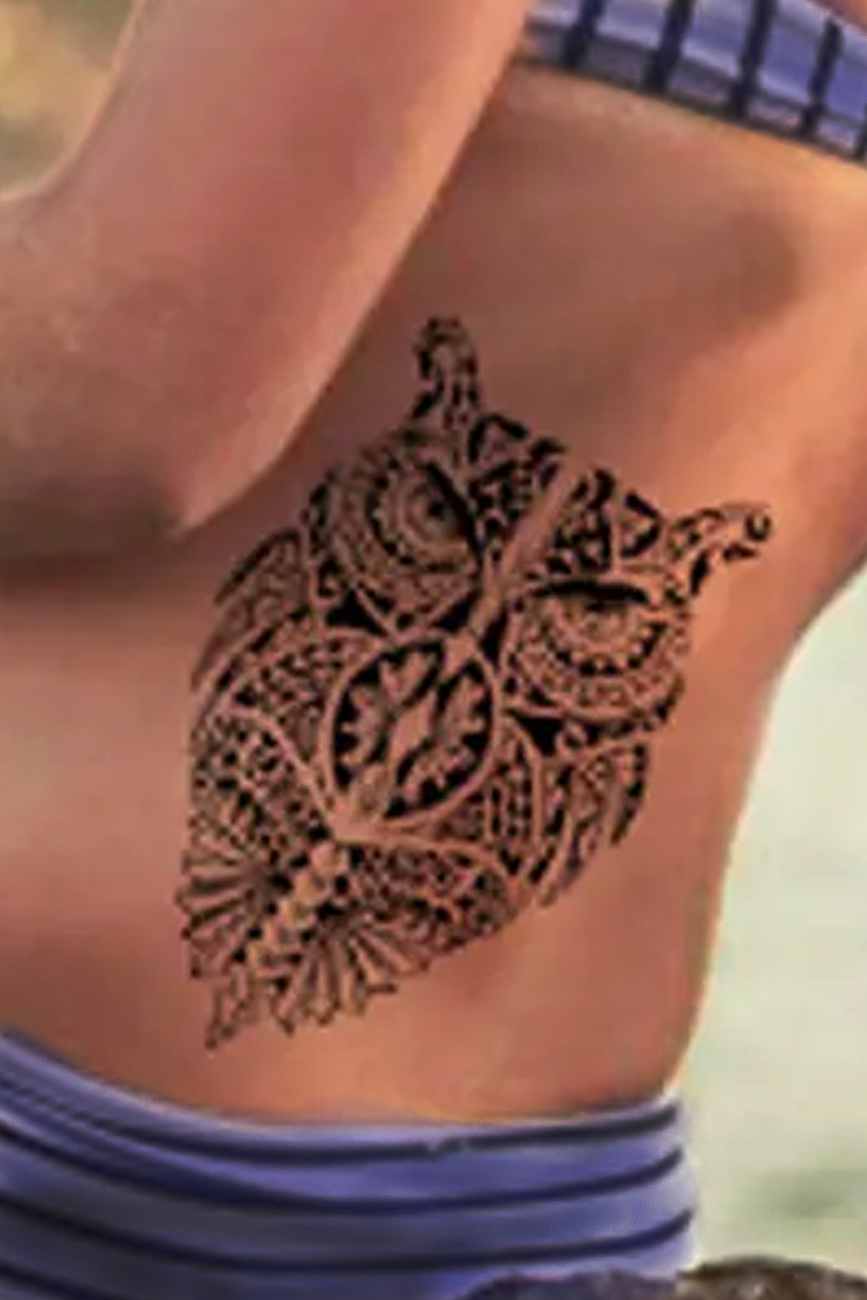 A female torso displays this tribal owl tat.