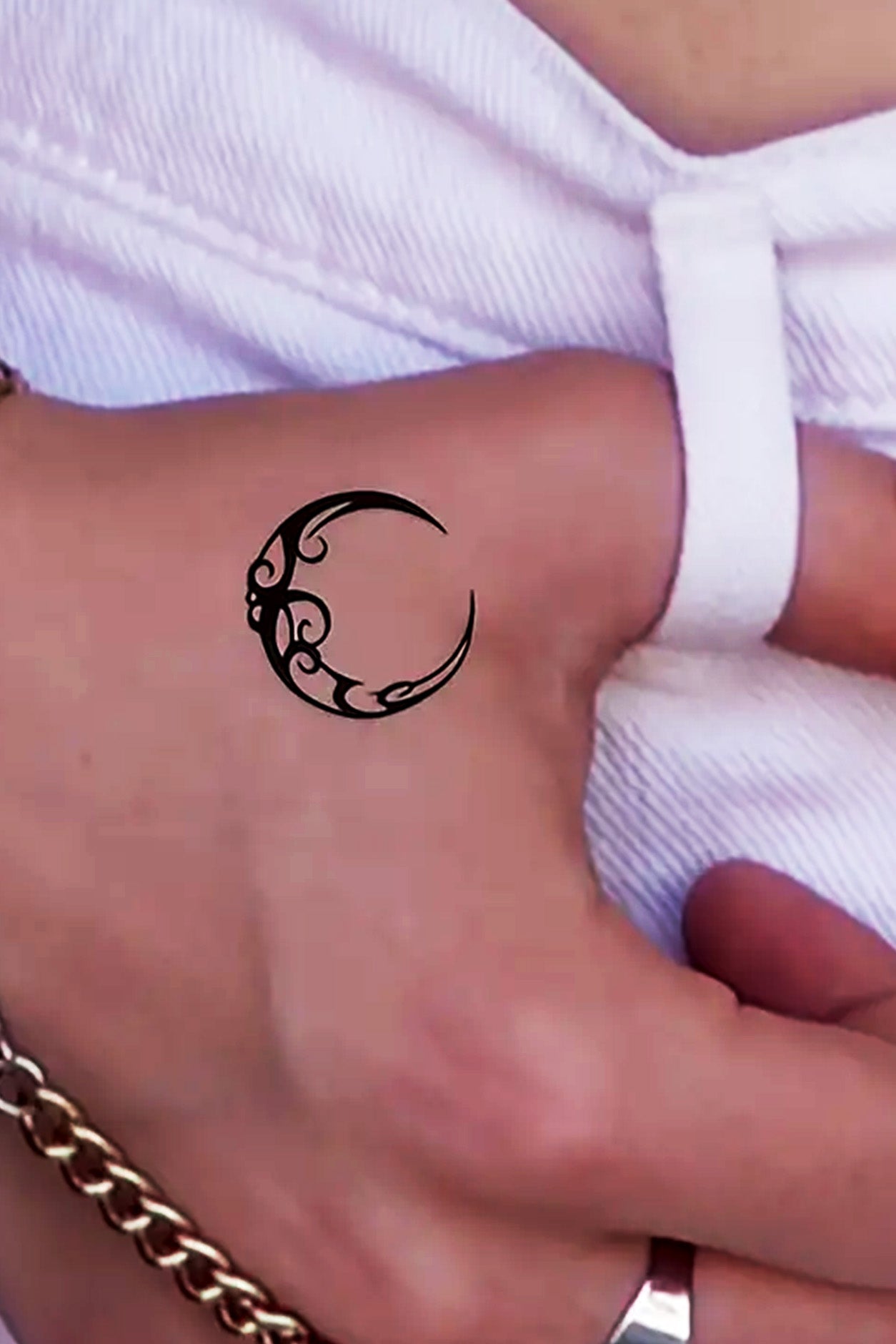 A gender-neutral arm displays a waning filigree moon on their hand. Choose from 18 more moon style designs.