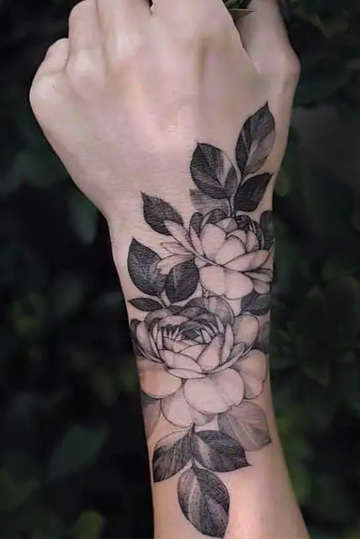 An arm displays this rose Temporary Tattoo, In the traditional black ink style, a gentle bouquet of two roses in a soft triangular shape. This artwork has the traditional feel and look of a realistic inked tattoo.   Creatively wear this artwork on any part of your body, arm, leg, torso, or shoulder.