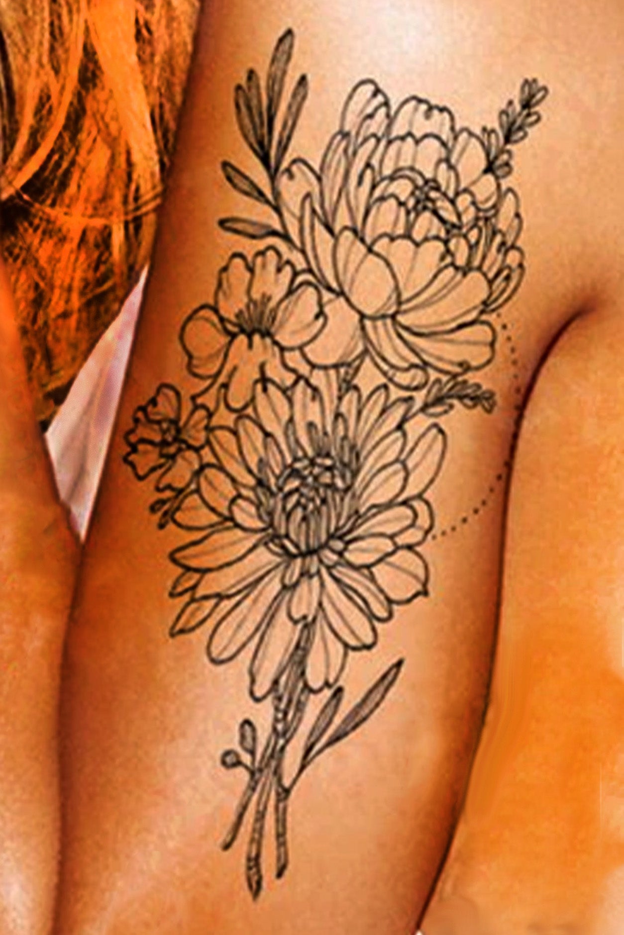 A gender-neutral arm displays the chrysanthemum bouquet artwork done in a traditionl black ink tattoo style.
