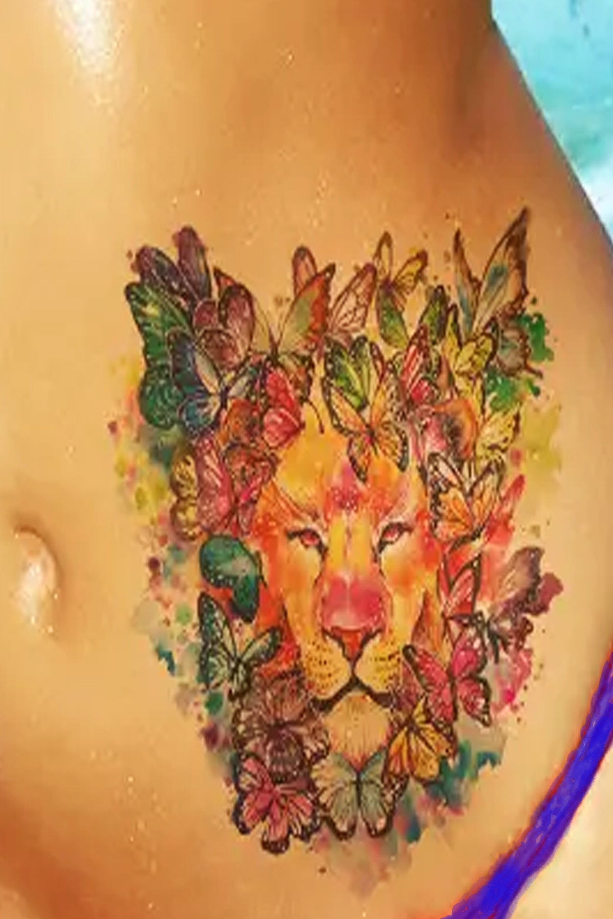 A torso displays the mighty lion covered in rainbow butterflies. No fear of being who you really are.