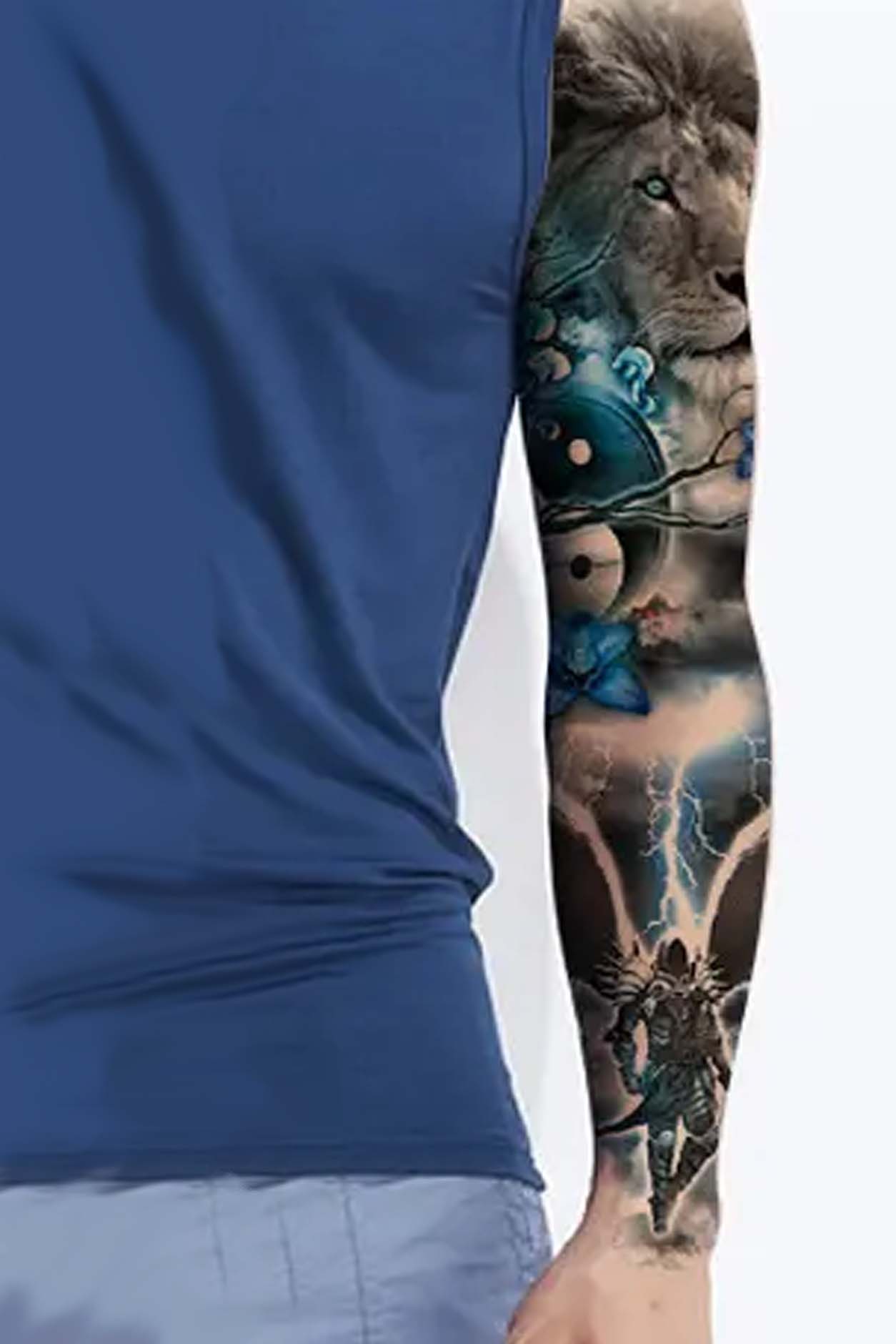 A guy is showing the full sleeve on his arm. In this temporary tattoo, the dark angel is descending from heaven. The lion represents power, strength, fearlessness, and strength in heaven above. The trees and flowers symbolize the beauty of the earth itself. This primarily black ink tat has accents of blue in the earthly items of flowers, lightning, and blossoms. Display this artwork on an arm, leg, or back.