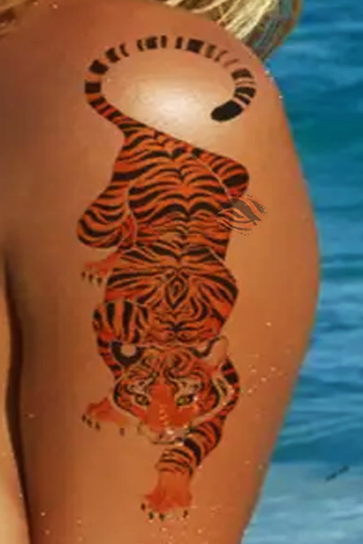 A gender-neutral arm displays the orange tiger. Big orange tigers are a sign of peace, harmony, and balance that compliments vacation time or a personal spirit in life. This full-body cat is slinking along, ready to pounce on prey with claws out. 
