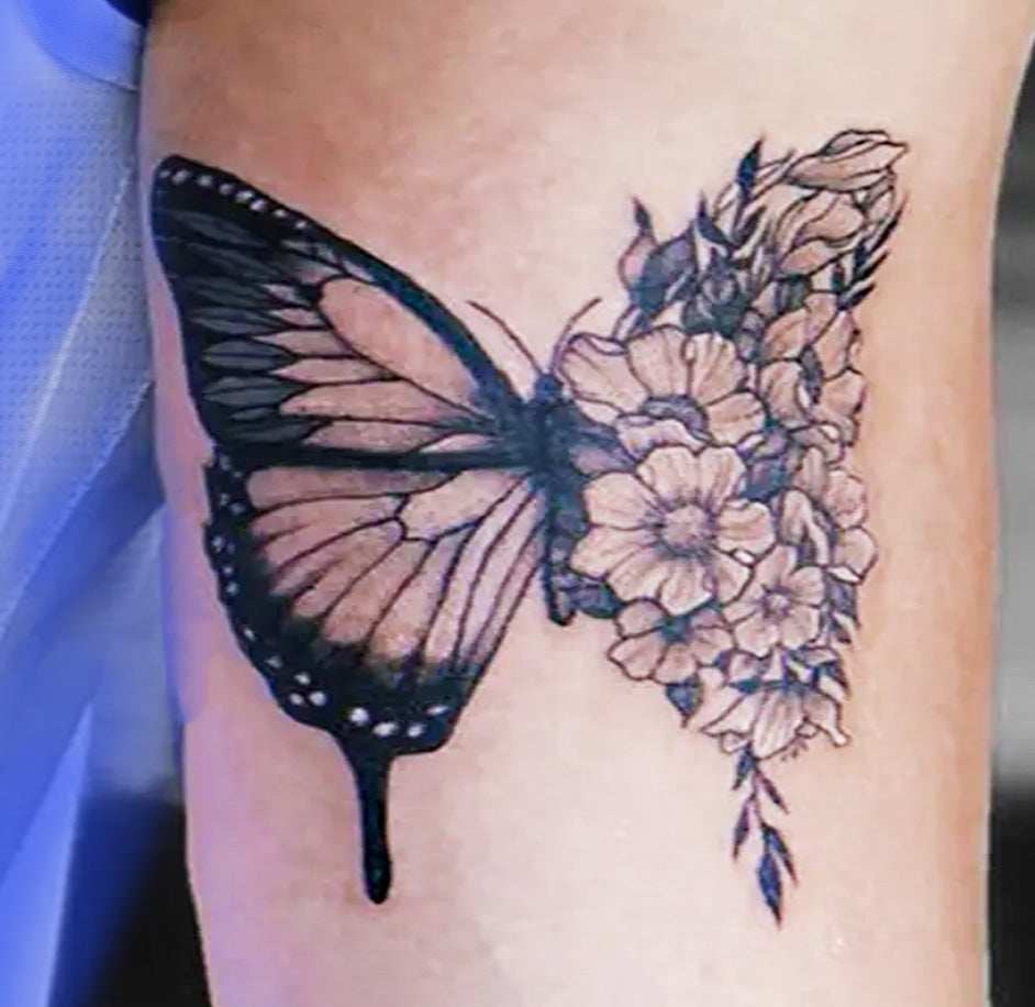 Arm with Butterfly flower tattoo attached. Soft and delicate as a Monarch butterfly. Similar to a traditional inked tattoo design is a Monarch butterfly; half of its wing is contrasted by detailed flowers.